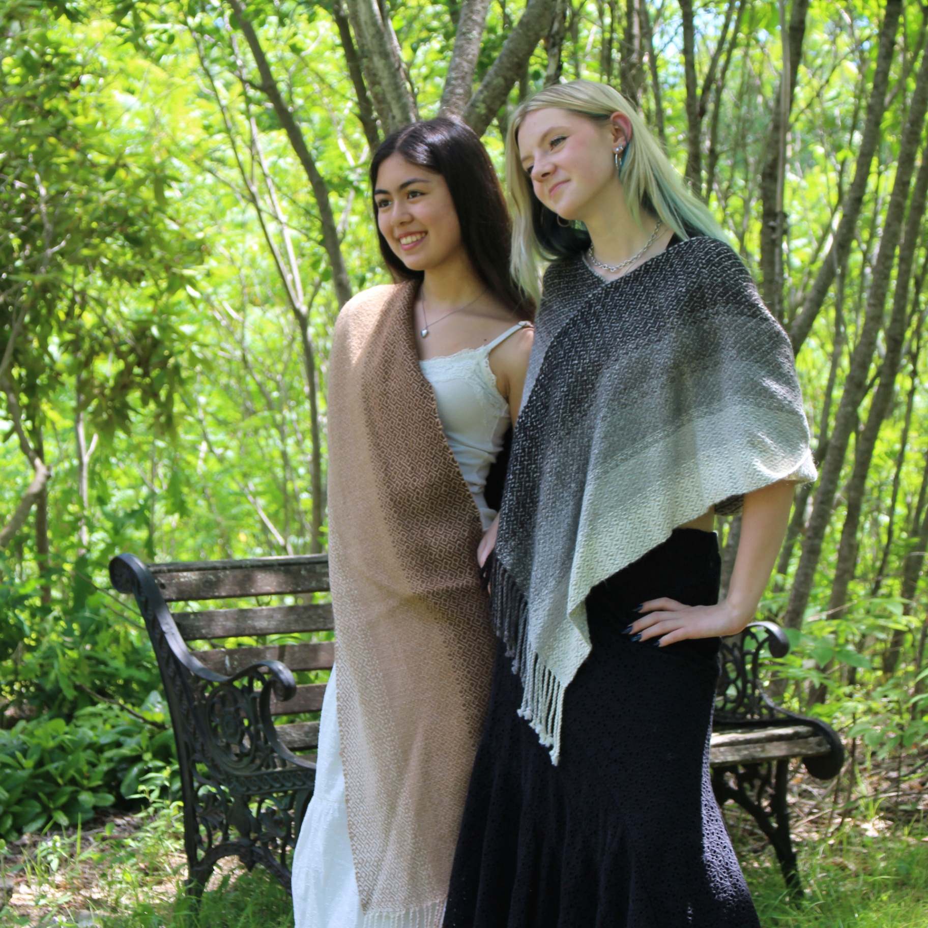 Two young women standing together in brown side-draped and gray alpaca ponchos