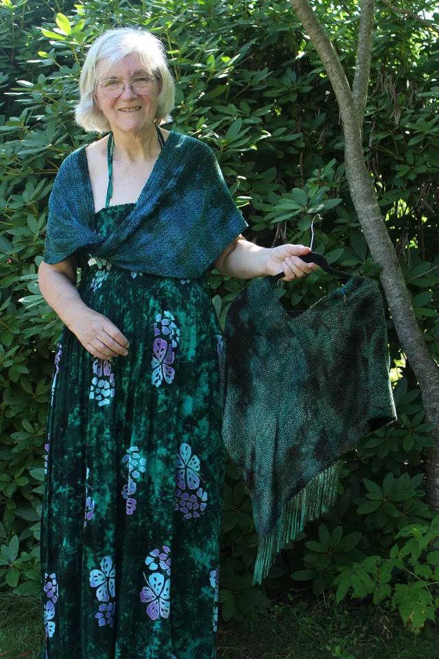 Woman wearing a deep teal chenille infinity poncho and holding a deep green one