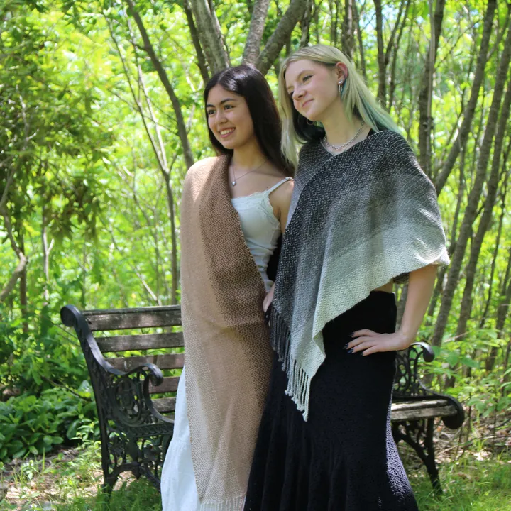 Two young women standing together in brown side-draped and gray alpaca ponchos