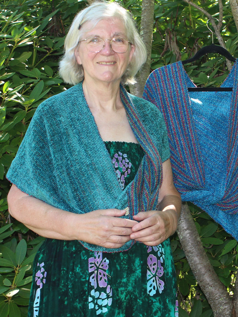 Woman wearing a teal infinity poncho, its reversible striped side also visible