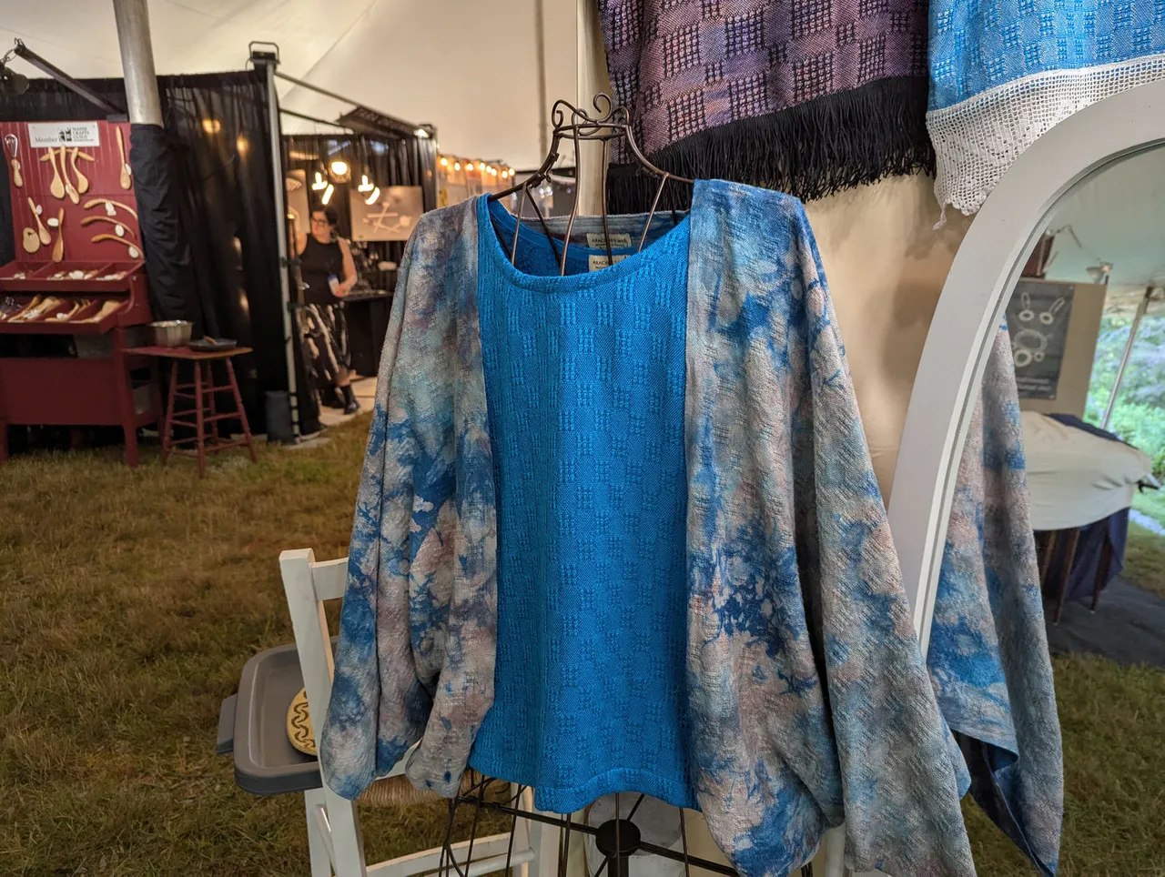 Hand-dyed turquoise and rose cocoon over a turquoise blouse at Frances's booth, other craftspeople's booths shown behind