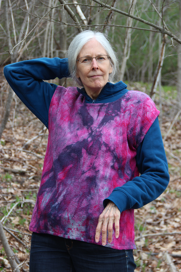 Woman wearing a hand-dyed blouse in brilliant deep pink and purple over a sweatshirt